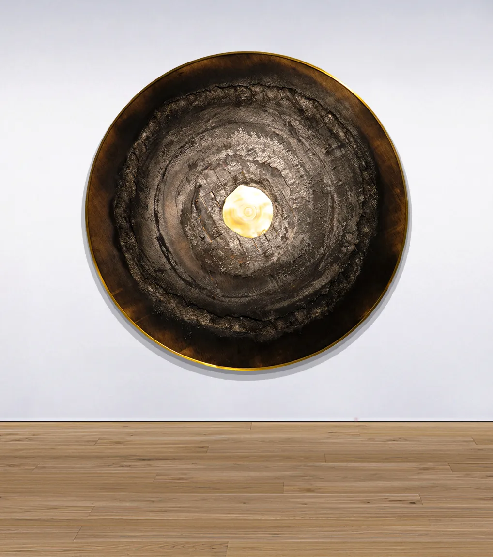 An installation view of the painting 'Heliocentrism' from 2021 by artist Damian Boylan. The painting from the Fire Paintings series shows carbonised wood and oxidised brass, mounted on a white gallery wall.
